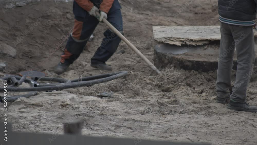 Workers digging shovels at a construction site, industry. Manual labor, work Workers digging shovels at a construction site, industry. Manual labor, work