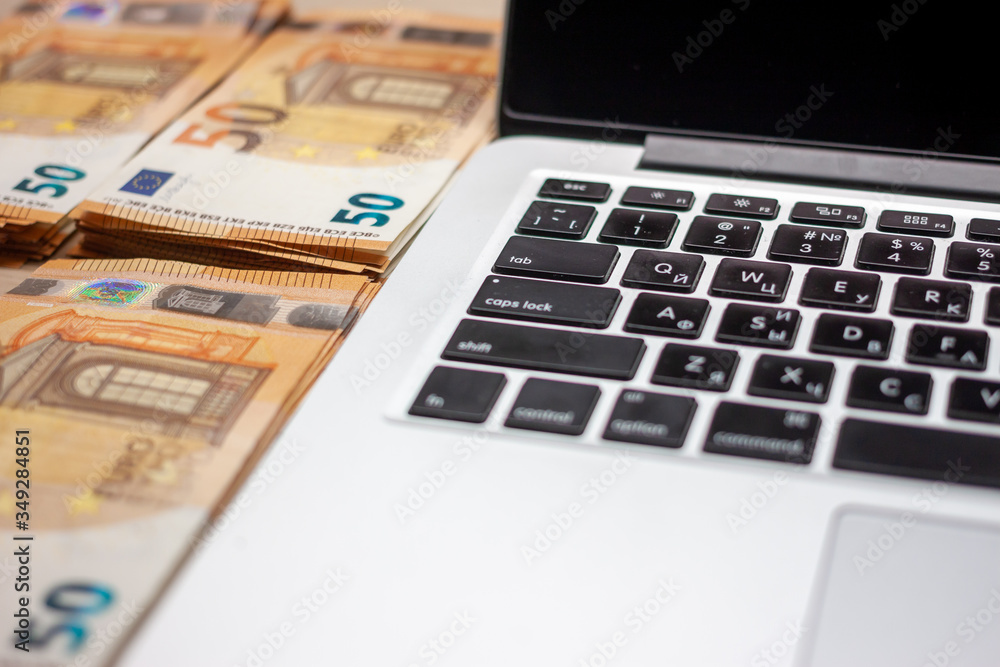 open laptop and stacks of money euro banknotes open laptop and stacks of money euro banknotes