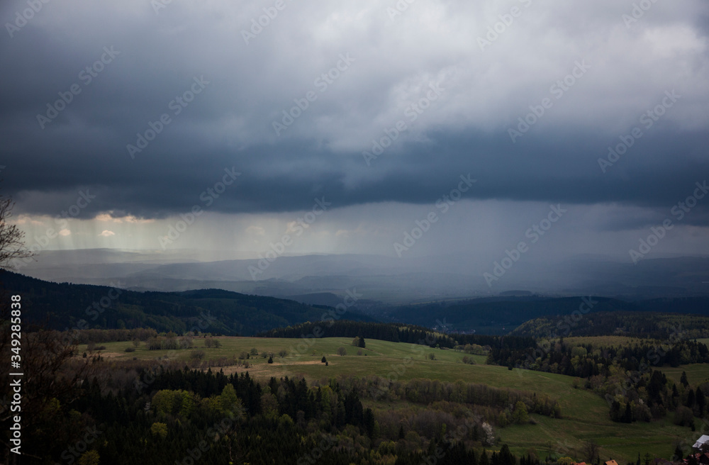 Obraz premium Black Rainy Clouds Cover The Forest And Grass Field