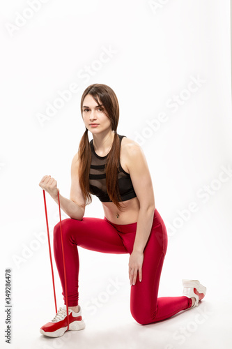 young, slim girl doing sport exercises with rubber expander isolated on white background