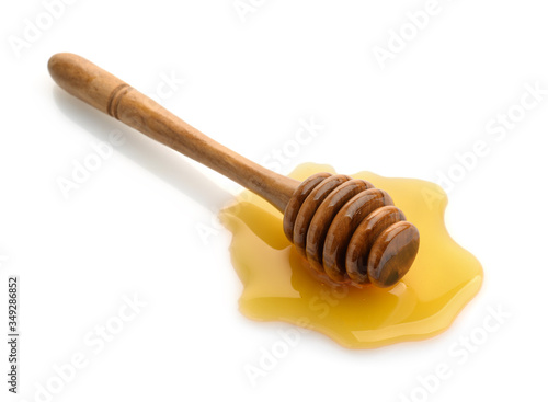 Wooden honey dipper in honey puddle