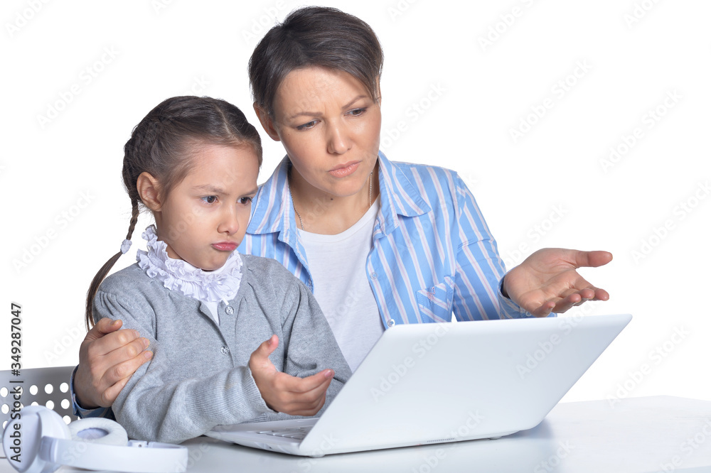 Portrait of emotional mother and daughter using laptop posing against white
