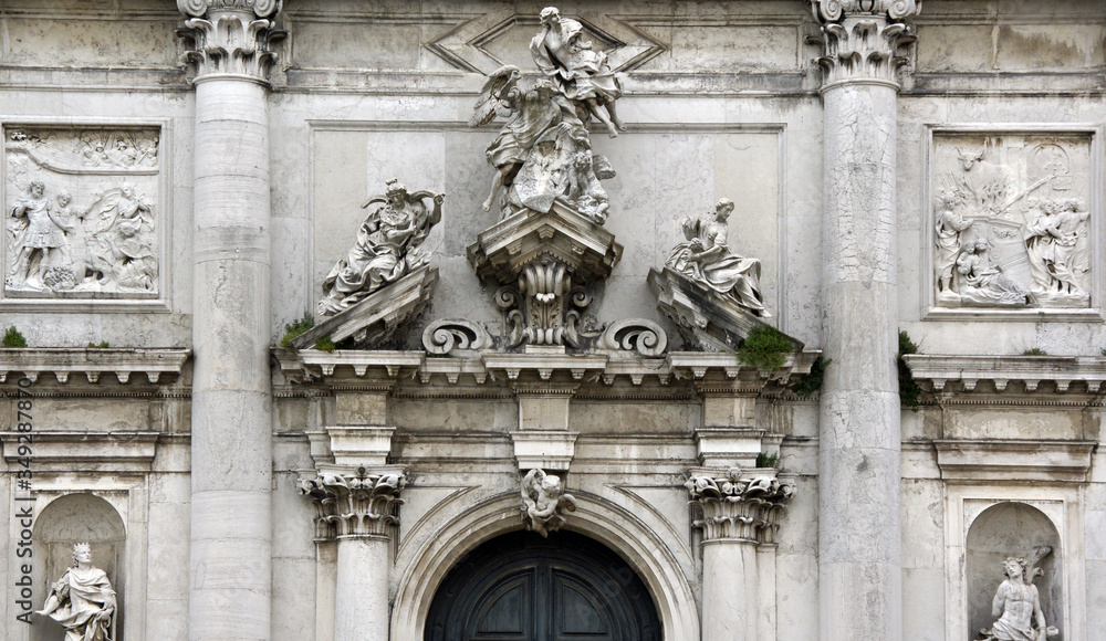 Photo of baroque marble facade in Venice with sculptures, columns, capitals, reliefs in historical part of Venice.