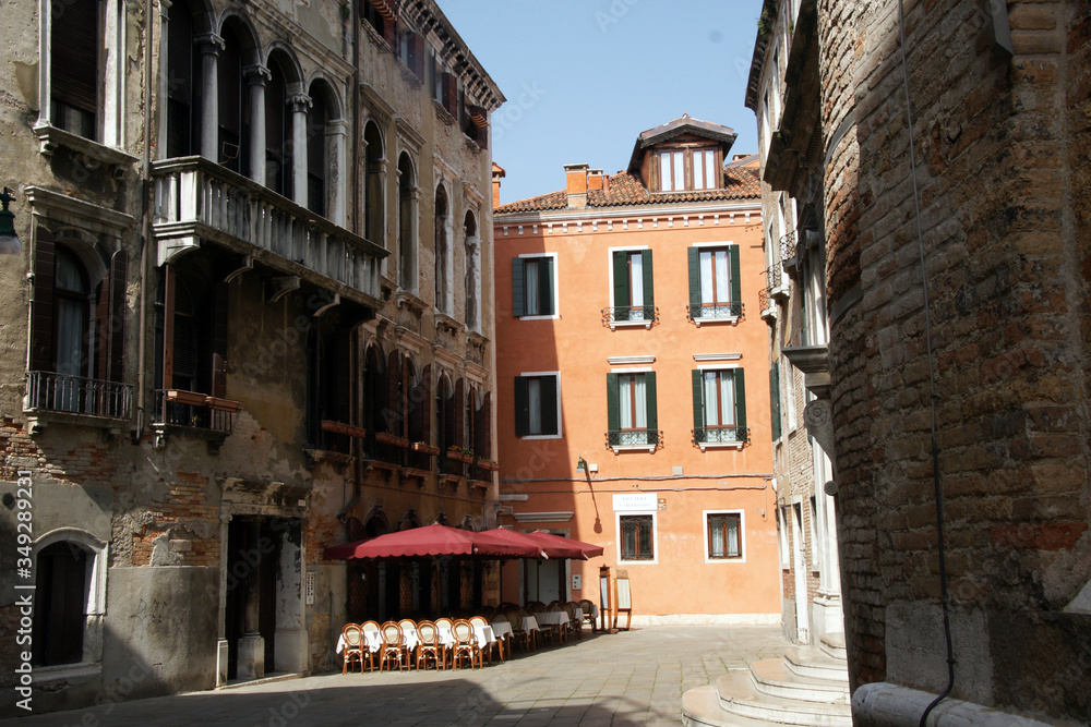 Photo of the street in Venice with historical facades and street restaurant.