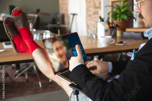 Videocall. Young man without pants but in jacket working on a computer, laptop. Remote office during coronavirus, fun and comfortable in underpants. Insulation, quarantine, humor, business concept. photo