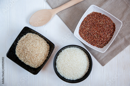 Different types of rice in cups on the table. White, brown and red.