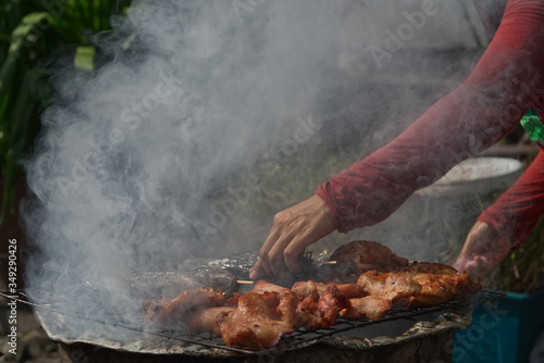 A person is arranging chicken stick on a charcoal stove