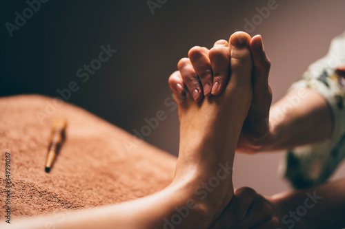 Professional foot massage close up. Authentic shot of luxury spa treatment. Charming light. Shallow depth of field. Stylized and colored. © gudenkoa