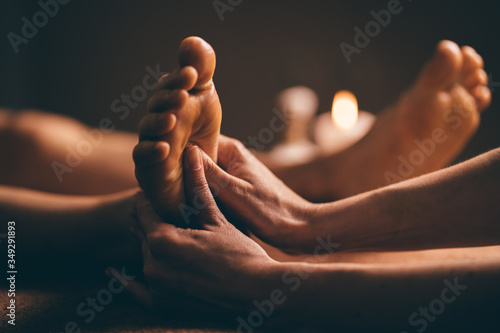 Professional foot massage close up. Authentic shot of luxury spa treatment. Charming light. Shallow depth of field. Stylized and colored. photo