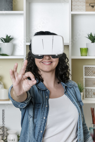 Happy lady in VR glasses gesturing OK