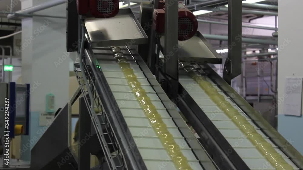An infinitely long caramel billet moves on a conveyor belt in a confectionery factory. An infinitely long caramel billet moves on a conveyor belt in a confectionery factory.