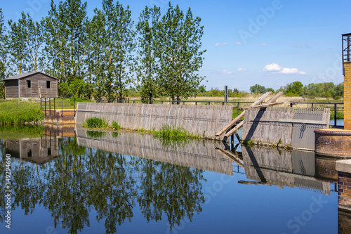 Obraz na płótnie View of an historical weir system. In the background there is a row of poplars. w salonie