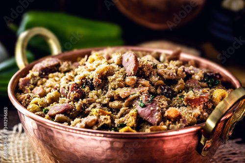 Beans with pork, called tropeiro beans, typical Brazilian food, state of Minas Gerais. Copper pot on rustic wooden background. photo
