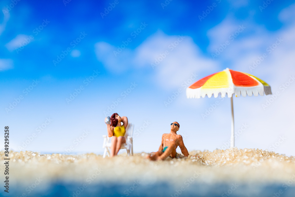 Miniature people sunbathing on The beach , Summer time concept