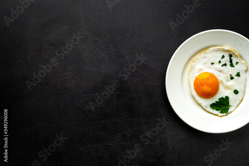 Fried eggs on plate - black dinner table from above copy space