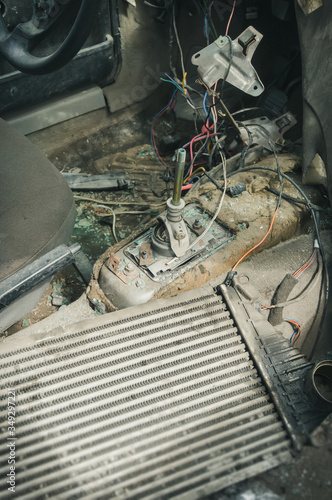 inside vertical view to gear shifter and wires of a broken and disassembled interior of old abandoned car at dump