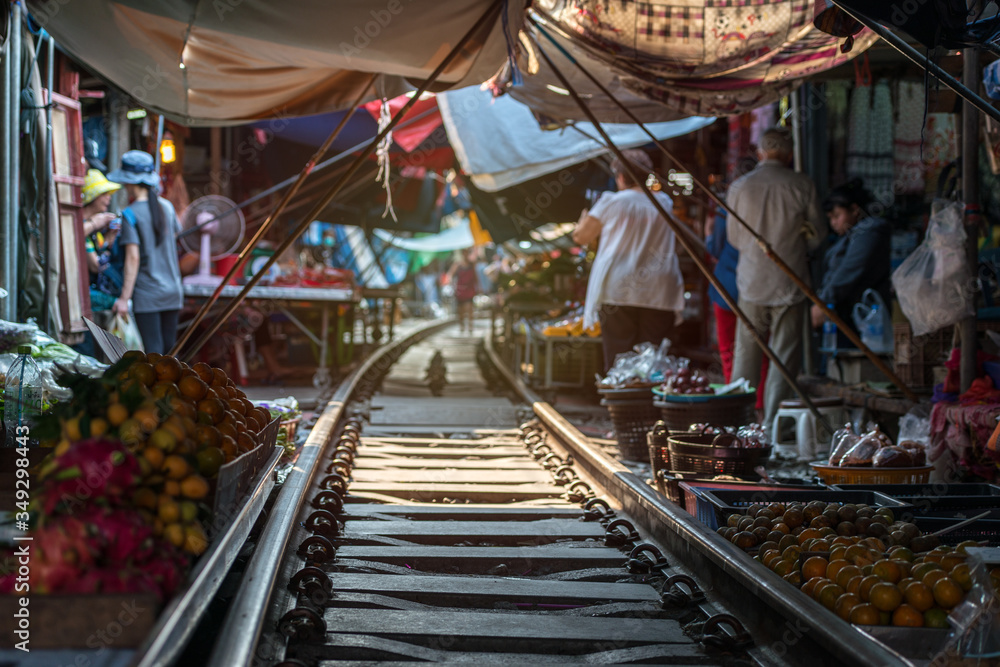 Thailand, Samut Songkhrami, Mae Klong railway market also called Siang Tai. Tourists walk along the train tracks. and make purchases from local sellers. Po place among tourists from all over the world