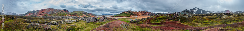 Panoramic view of colorful volcanic Landmannalaugar mountains, camping site and trail path at dramatic sky in Iceland, summer, wide angle