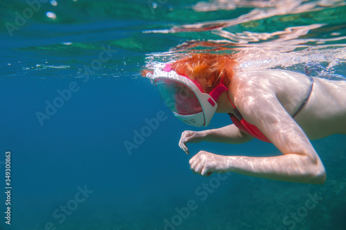 Girl in a full-face mask for snorkeling. Under the water. dives to the bottom. having fun at sea. vacation and rest at sea. bright colours. Copy space © Sergey