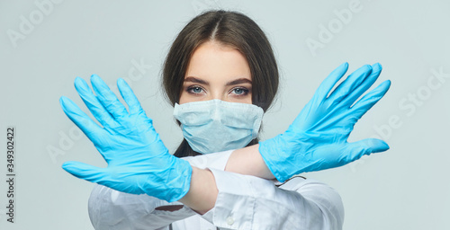 Covid19, coronavirus, a concept of healthcare and doctors. Portrait of a female doctor who shows a stop gesture! puts on a medical mask to prevent infection with the virus