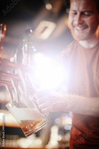 Closeup of bearded ginger bartender filling pint with beer.
