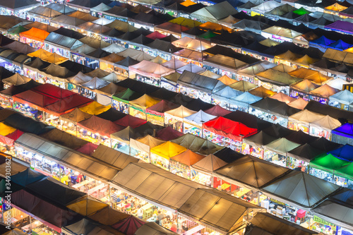 Bangkok, Thailand, Top view of Train Night Market Ratchada flea market with plenty of shops with colorful canvas and amazing pattern of roofs near MRT line at night time in Bangkok