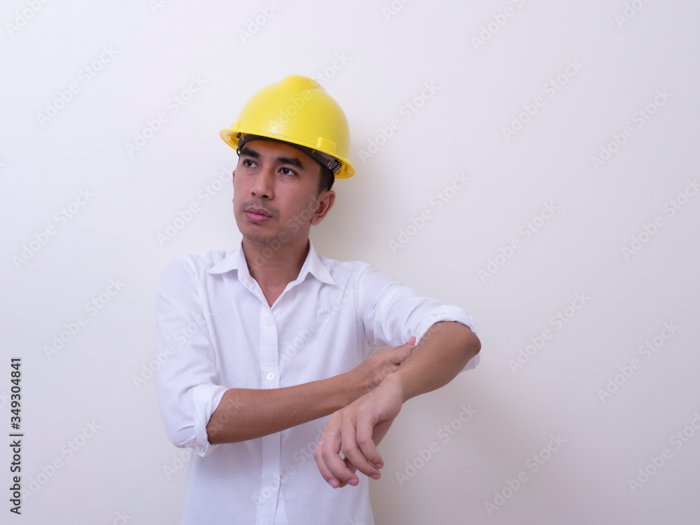 engineer with hands crossed wearing yellow helmet on white background