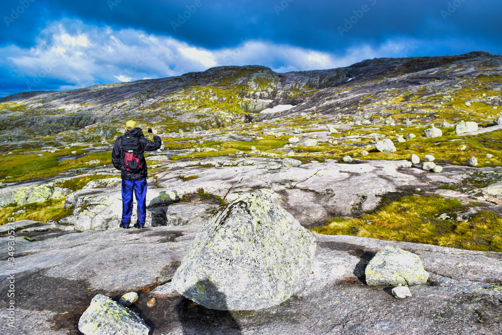 Tourist man on trail to Kjeragbolten. Amazing landscapes of the Norwegian mountains.