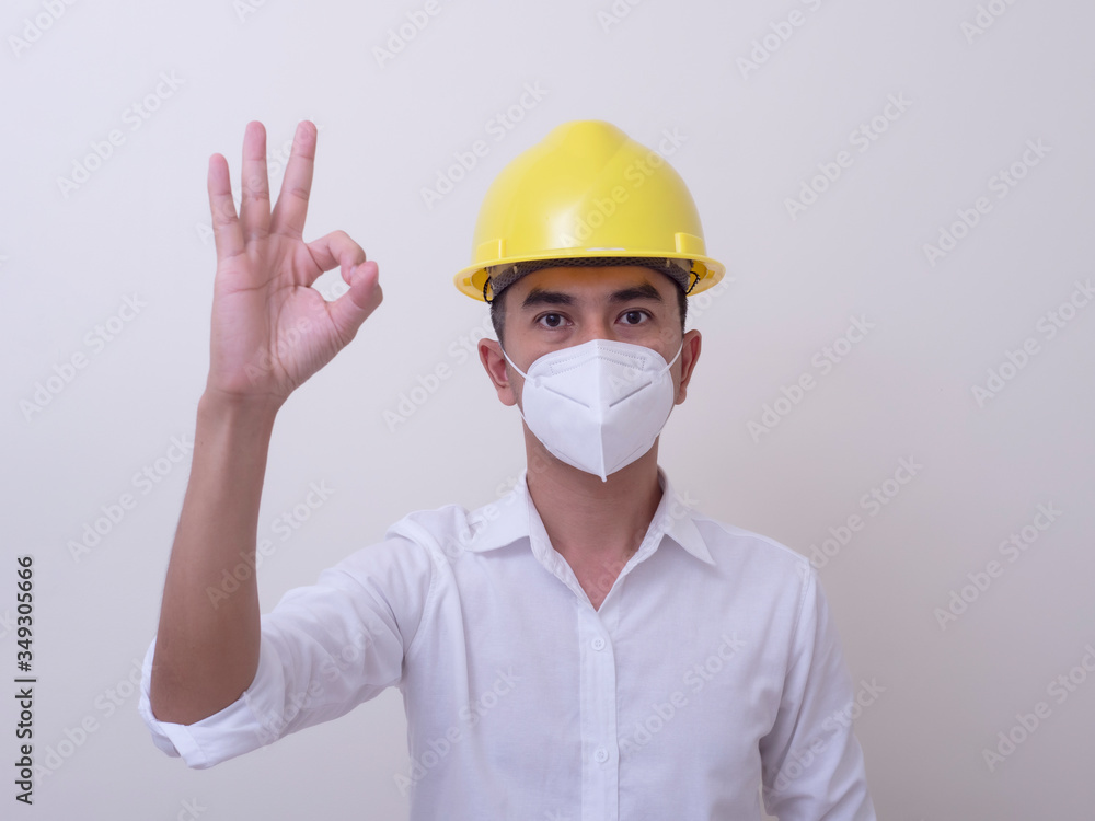 Asian industrial workers wear yellow hard hats, wear protective masks for their health Asian industrial workers wear yellow hard hats, wear protective masks for their health