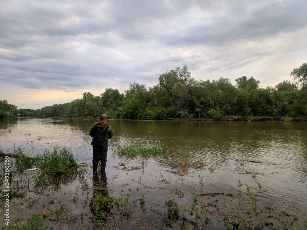 an experienced fisherman in rubber boots, fishing on the Siberian river