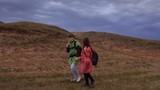 free female travelers go to gorge, holding hands. teamwork travelers. Healthy tourist girls travel with backpacks in colorful raincoats, storm is approaching. concept of adventure and travel.