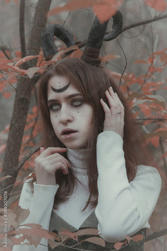 Fototapeta premium Gloomy girl with horns in the forest. Halloween image