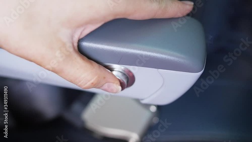 woman pushing airplane seat recline button several times