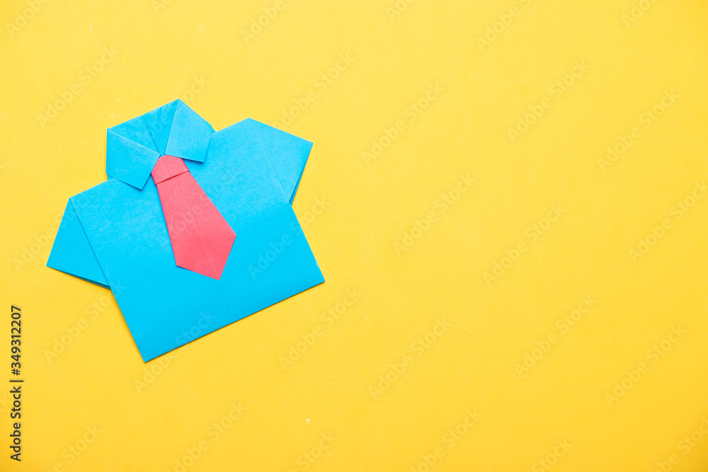 Blue shirt with a pink tie made using the origami technique on a yellow background. DIY concept. Blue shirt with a pink tie made using the origami technique on a yellow background. DIY concept.