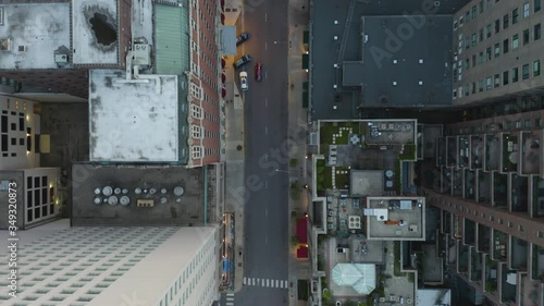 Red Car Drives between Skyscrapers on Empty One Way Street, Birds Eye Aerial
