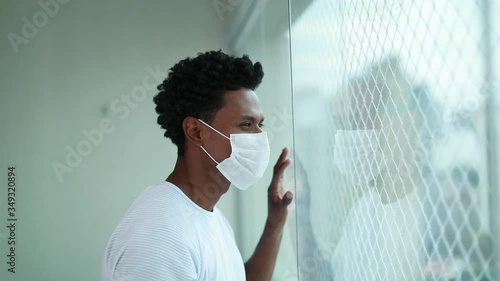 African american black man standing next to window looking outside city wearing covd mask photo