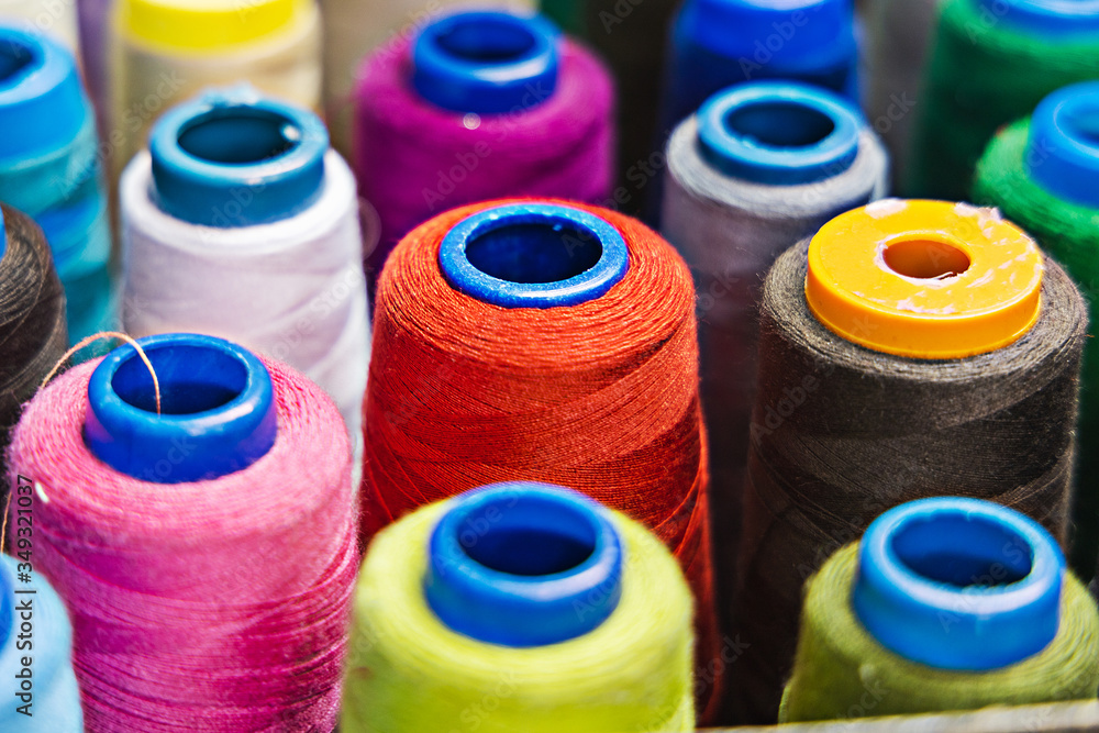A pile of sewing reels with threads of different colors. Closeup. Side view. Background A pile of sewing reels with threads of different colors. Closeup. Side view. Background