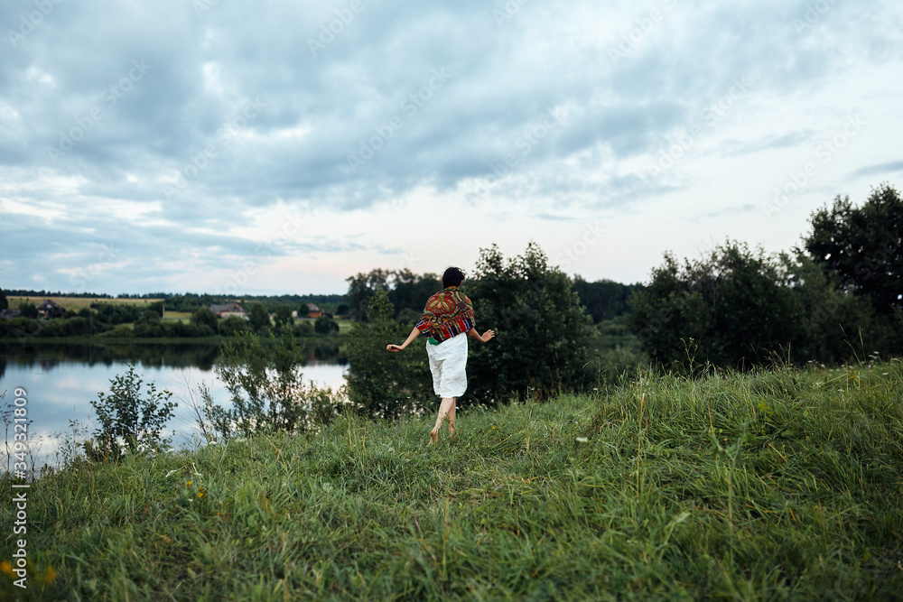 A girl runs along a lush green field to a pond A girl runs along a lush green field to a pond