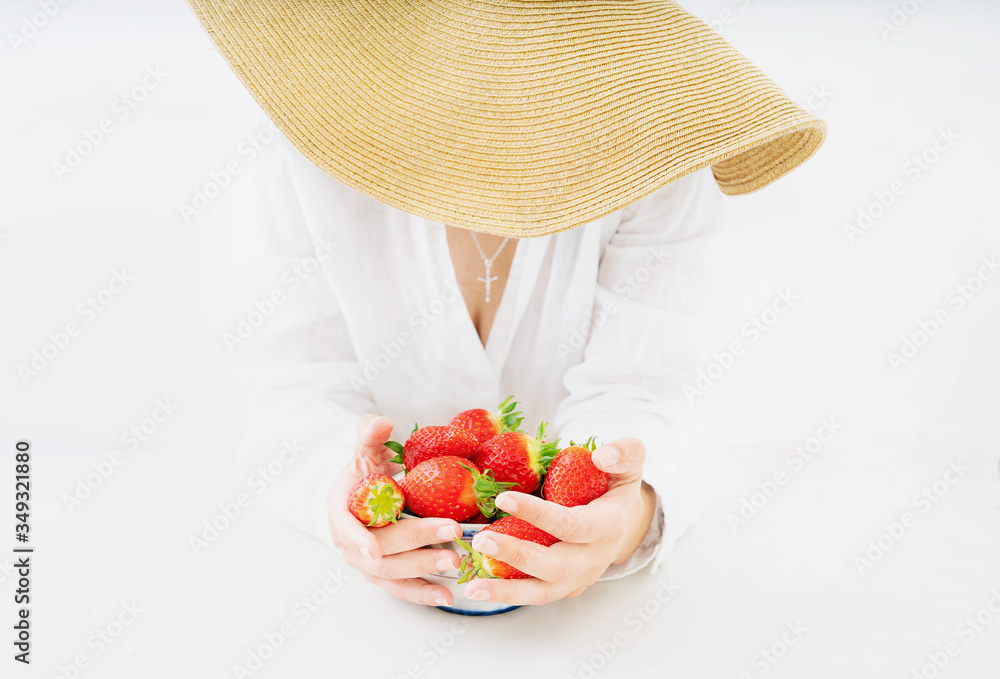 Young woman in summer hat with a bowl of fresh strawberries Young woman in summer hat with a bowl of fresh strawberries