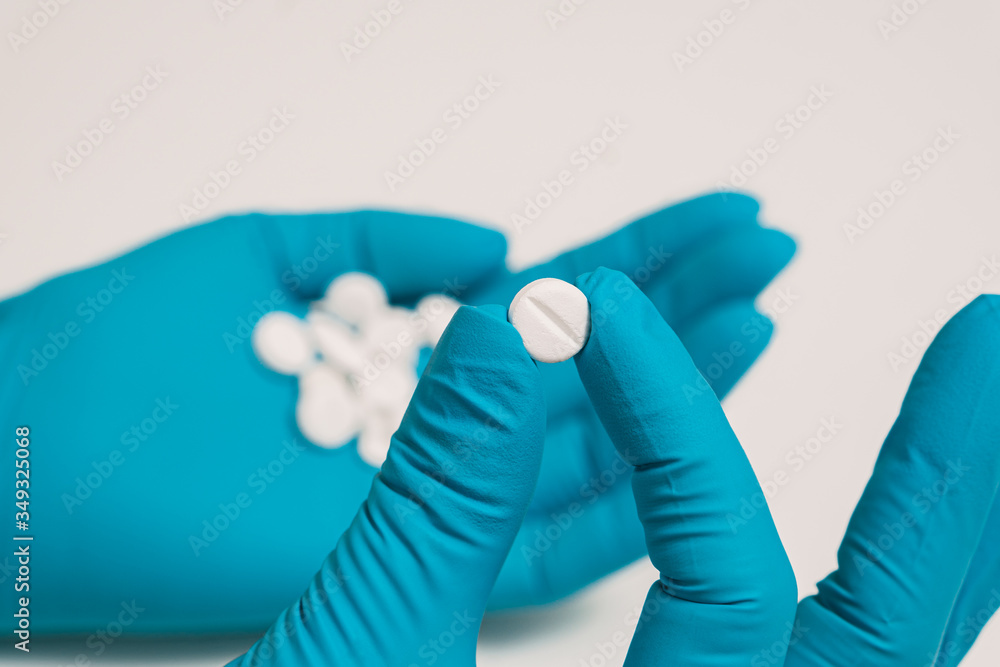 The doctor's blue-gloved hand holds the medicine. The doctor's blue-gloved hand holds the medicine.