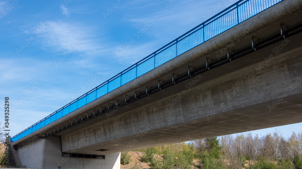 Neue Betonbrücke vor blauem Himmel und blauem Geländer Neue Betonbrücke vor blauem Himmel und blauem Geländer