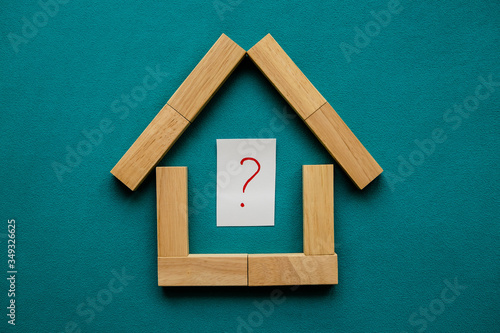 House made of wooden blocks with a red question mark inside on a blue background. Flat lay, top view, copy space.