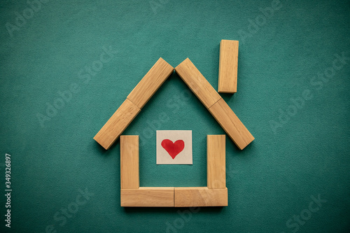 House made of wooden blocks with a red heart inside on a blue background. Flat lay, top view, copy space.