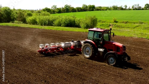 aerial view tractor cuts furrows in farm field for sowing farm tractor with rotary harrow plow preparing land for sowing. Tractor with harrows prepares the agricultural land for planting crop