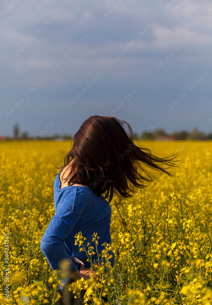 Young woman in rape field swinging with hair Young woman in rape field swinging with hair