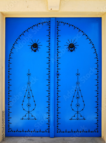 Tunisian blue metal traditional door with a black pattern and doorknobs