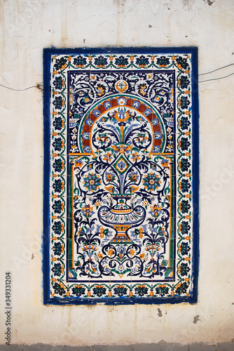 Tunisian traditional mural in the form of ceramic tiles on a white cracked wall of an old house