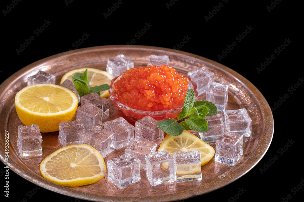 Red salmon caviar on plate with fresh lemon, ice cube, mint. Healthy diet. Selective focus Copy space Space for text Red salmon caviar on plate with fresh lemon, ice cube, mint. Healthy diet. Selective focus Copy space Space for text