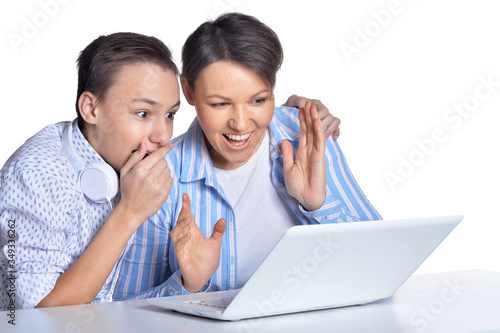 Portrait of happy mother and son using laptop posing against white