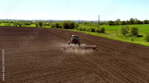 aerial view tractor cuts furrows in farm field for sowing farm tractor with rotary harrow plow preparing land for sowing. Tractor with harrows prepares the agricultural land for planting crop